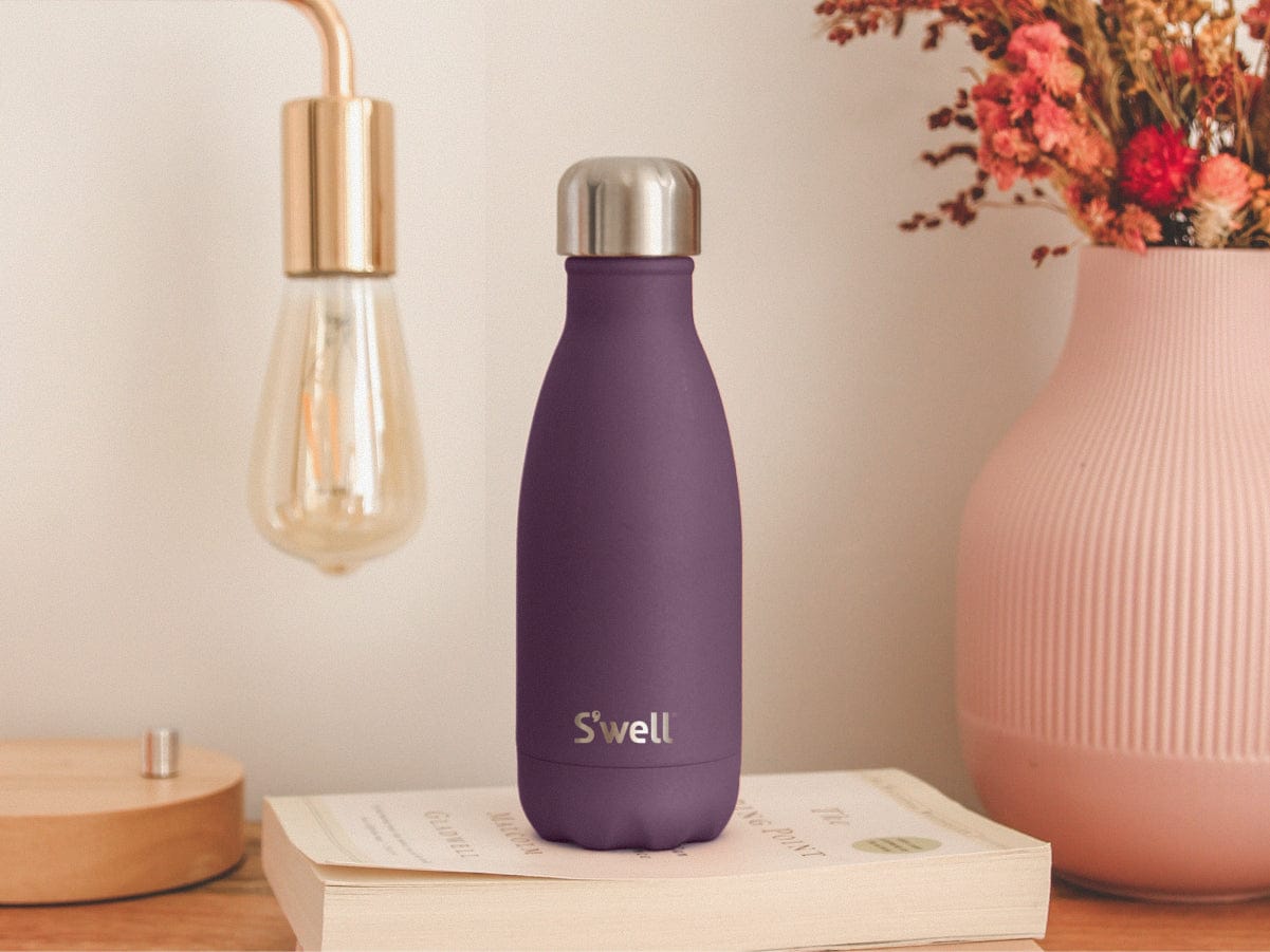 plum 9oz Original Bottle sitting on desk with book